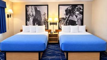 Une chambre d’hôtel avec deux lits, une moquette bleue et deux lampes fixées au mur.