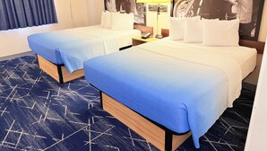 Hotellihuone, jossa on kaksi sänkyä, suuri ikkuna, jossa on verhot, lamppu ja seinään kiinnitetty puhelin.