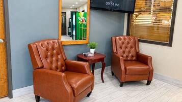 A room with two brown leather armchairs, a small table with a plant, and a flat-screen TV mounted on the wall displaying the LG logo.