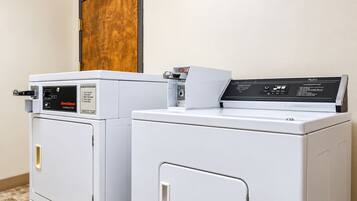 Two front-loading washers in a laundry room with a wooden door above.