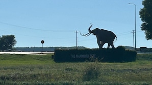 A large elephant sculpture on a grassy field with a sign that reads "The Mammoth Site". - Super 8 by Wyndham Hot Springs (Hot Springs)