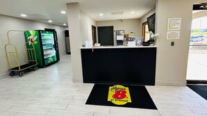 Aula, jossa on vastaanottotiski, 7UP-juomajääkaappi ja kultainen kärry.