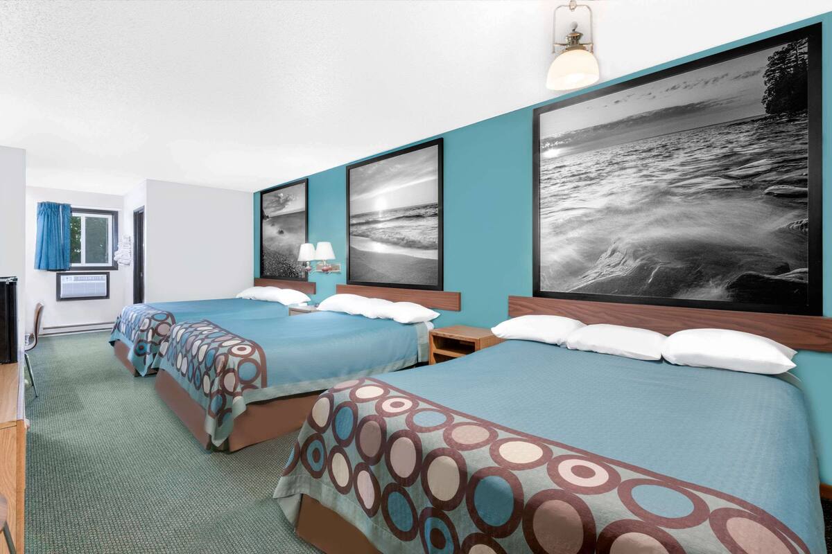 A hotel room with two beds, a desk, and a chair.