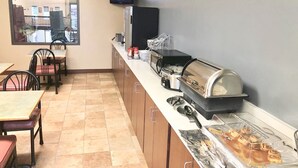 Una barra de desayuno con microondas, tostadora y cafetera. Hay sillas y mesas en la habitación.