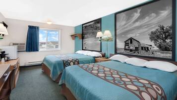 A hotel room with two beds, a desk, a chair, a window with curtains, a wall-mounted lamp, and a large framed picture.