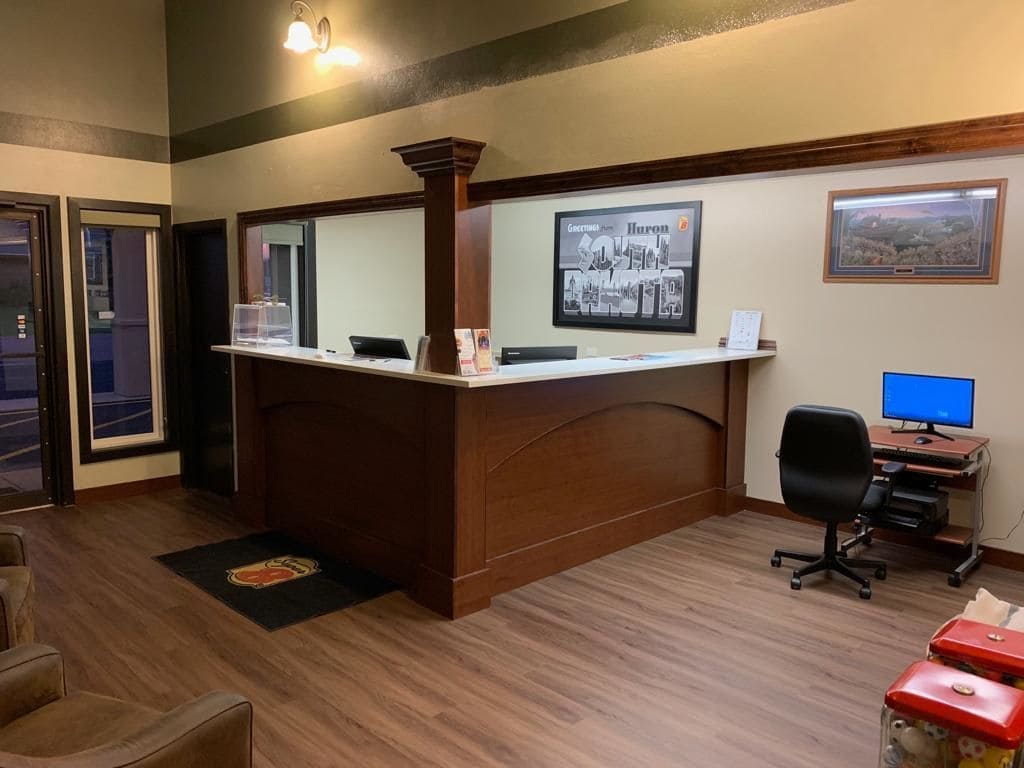 A reception desk with a computer, a framed picture on the wall, and a desk lamp.