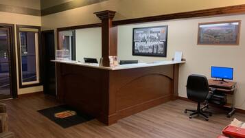 A reception desk with a computer, a framed picture on the wall, and a desk lamp.