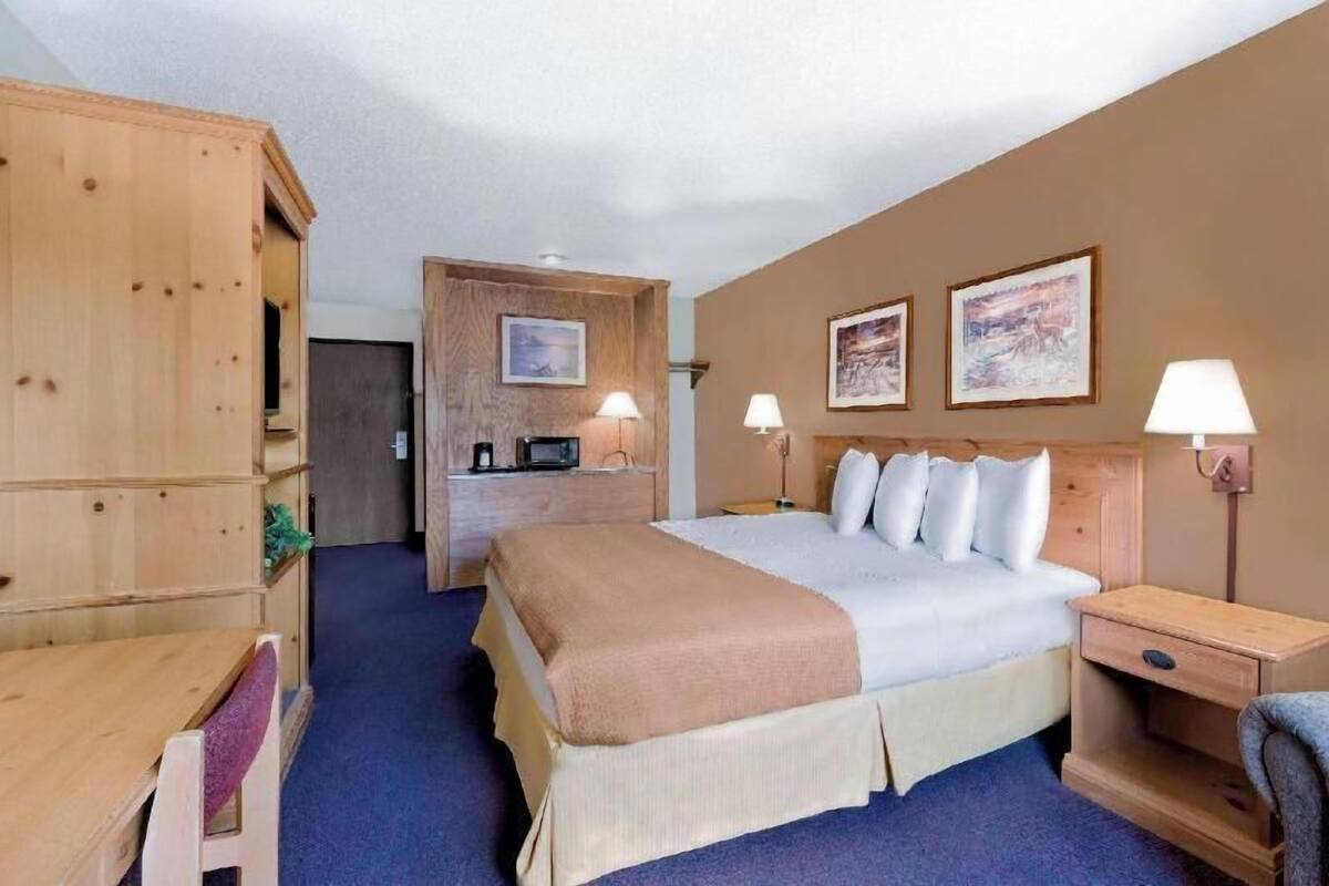 A hotel room with a bed, bedside tables, a desk, a wardrobe, and a kitchenette.