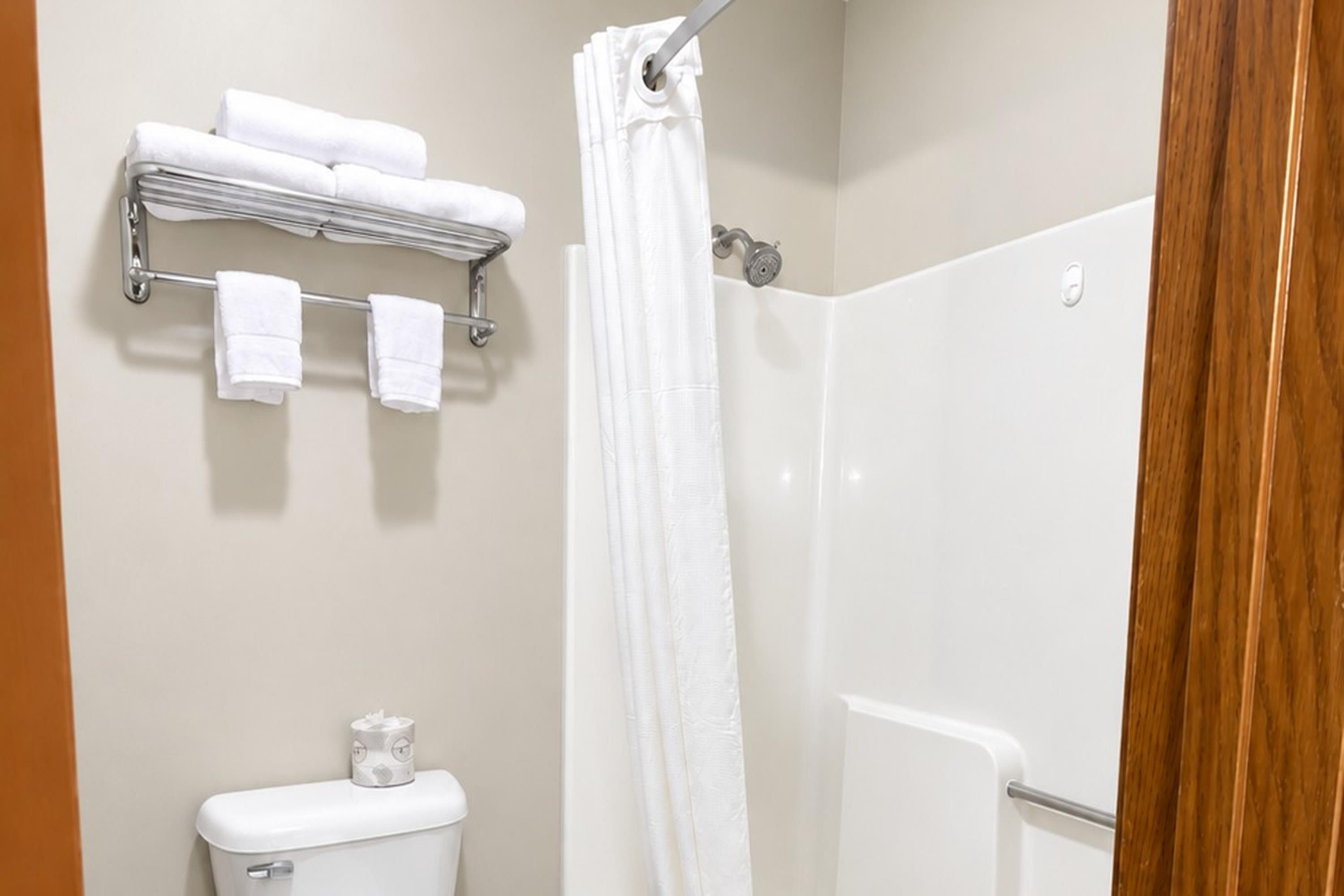 A bathroom with a toilet, a shower, and a towel rack with towels.