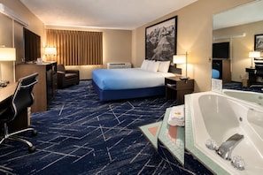 Una habitación de hotel con cama, escritorio, silla y baño con bañera.