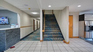 Un hall d’hôtel comprenant un comptoir d’accueil, un escalier et un coin cuisine.