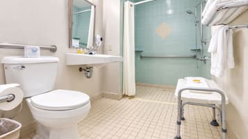 A bathroom with a toilet, sink, shower, and grab bars.