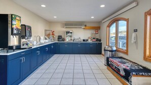 Une cuisine avec des meubles de couleur bleue, une machine à café, un four à micro-ondes et une grande fenêtre.