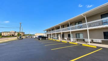 Un motel con estacionamiento, un edificio de dos pisos y un cielo azul despejado.