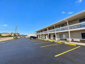 A motel with a parking lot, a two-story building, and a clear blue sky.