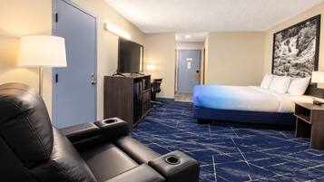 A hotel room with a bed, a desk, a chair, a TV, and a painting on the wall.