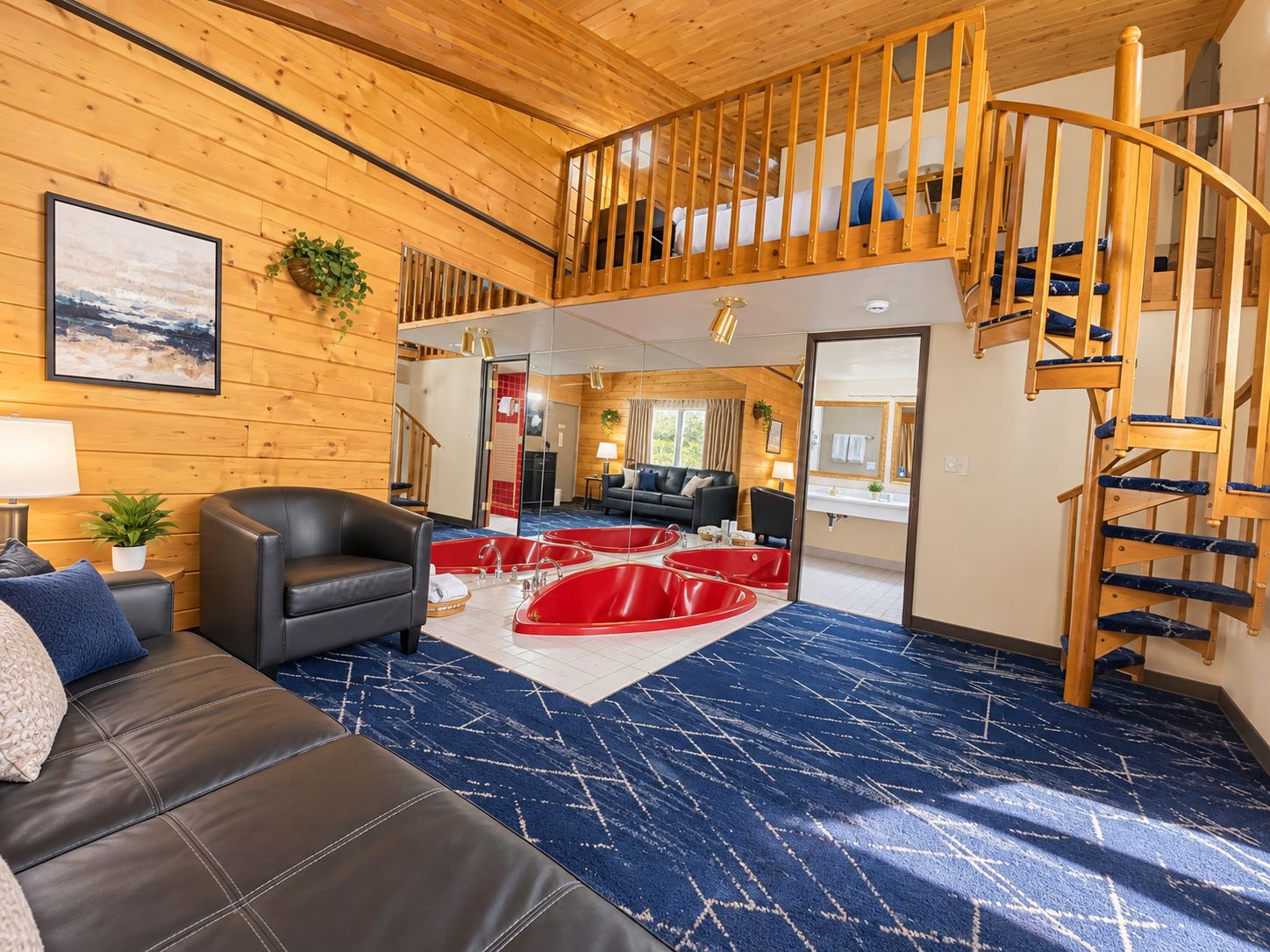A spacious living area with a black leather sofa, a red jacuzzi, and a wooden staircase.