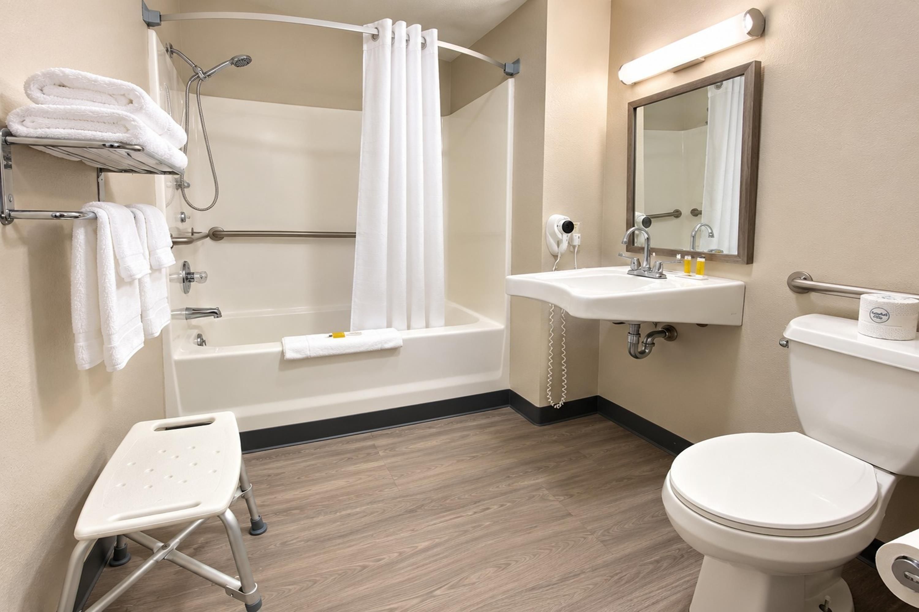 A bathroom with a bathtub, toilet, sink, and a small step stool.