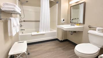 A bathroom with a bathtub, toilet, sink, and a small step stool.