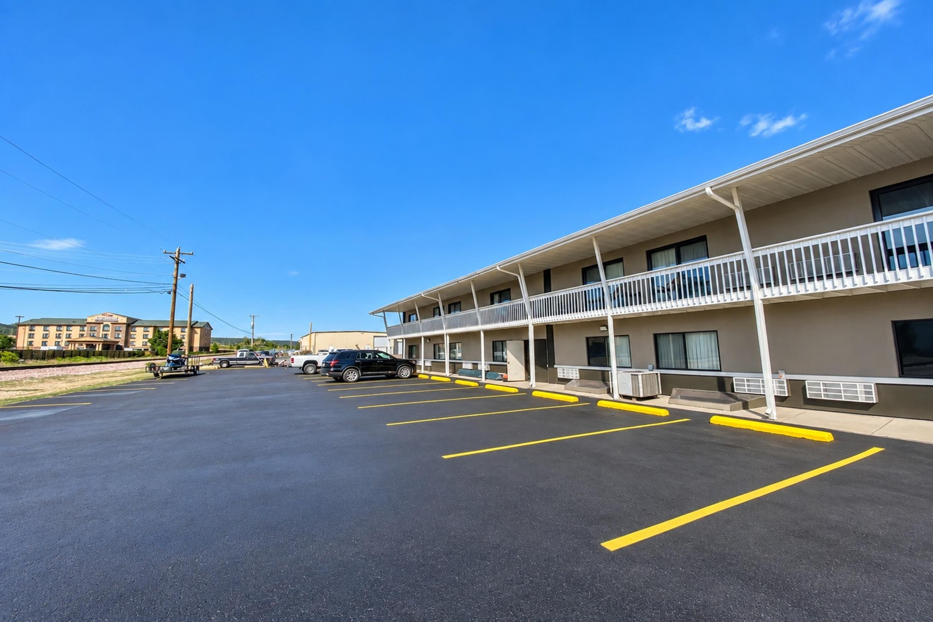 A motel with a parking lot, a building with multiple balconies, and a clear sky.