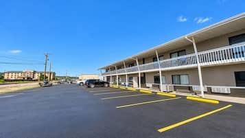 A motel with a parking lot, a building with multiple balconies, and a clear sky.