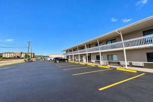 A motel with a parking lot, a building with multiple balconies, and a clear sky.
