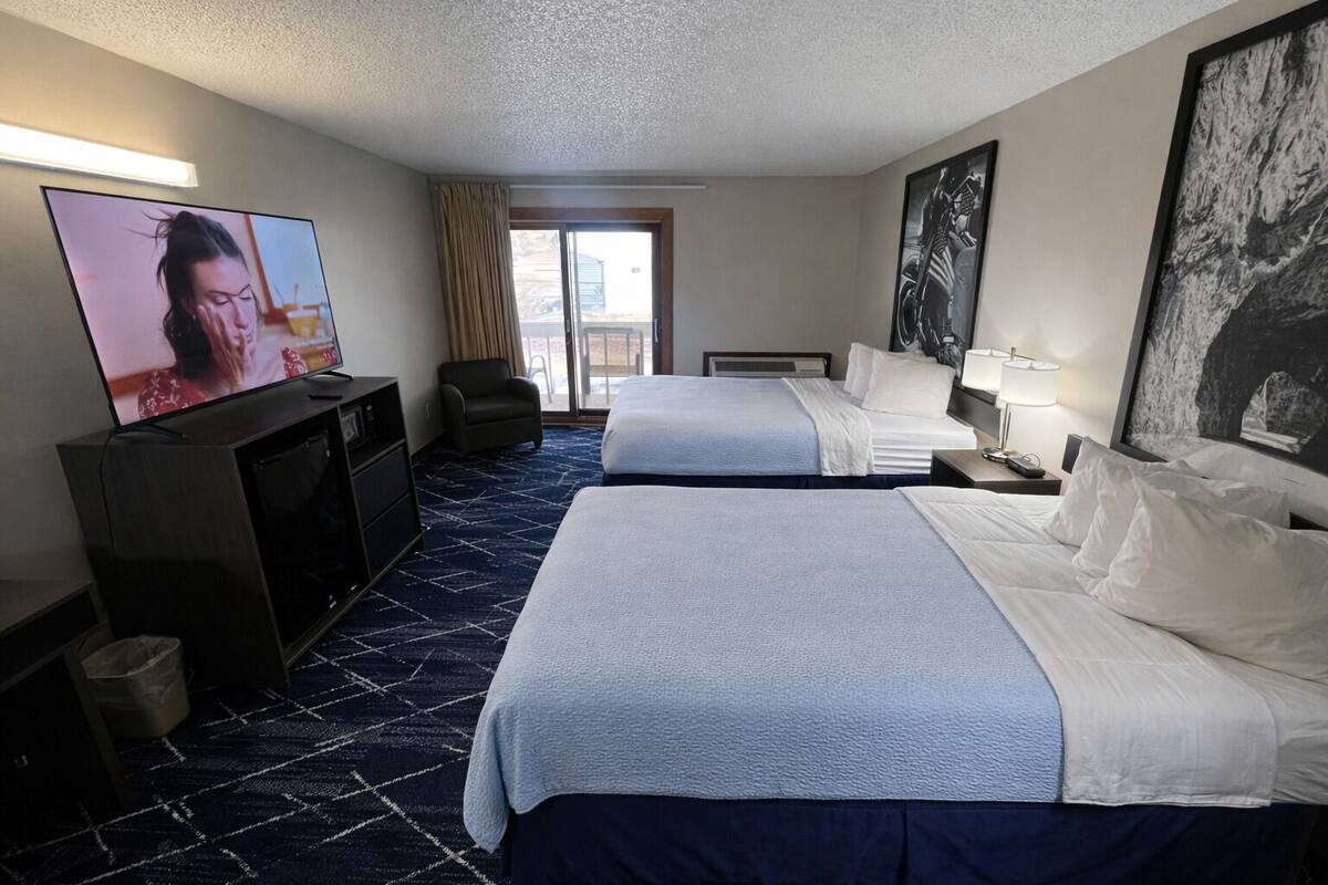 Une chambre d’hôtel avec deux lits, une télévision, un bureau et une chaise.