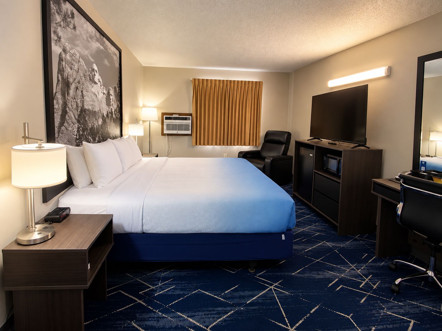 A hotel room with a bed, a desk, a chair, a TV, and a large painting on the wall.
