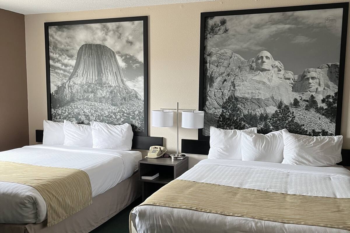 Une chambre d’hôtel avec deux lits, une table de chevet avec une lampe et de grandes images encadrées au mur.