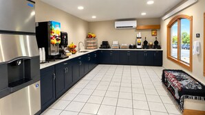 A modern kitchen with a refrigerator, coffee machine, and a fruit bowl.
