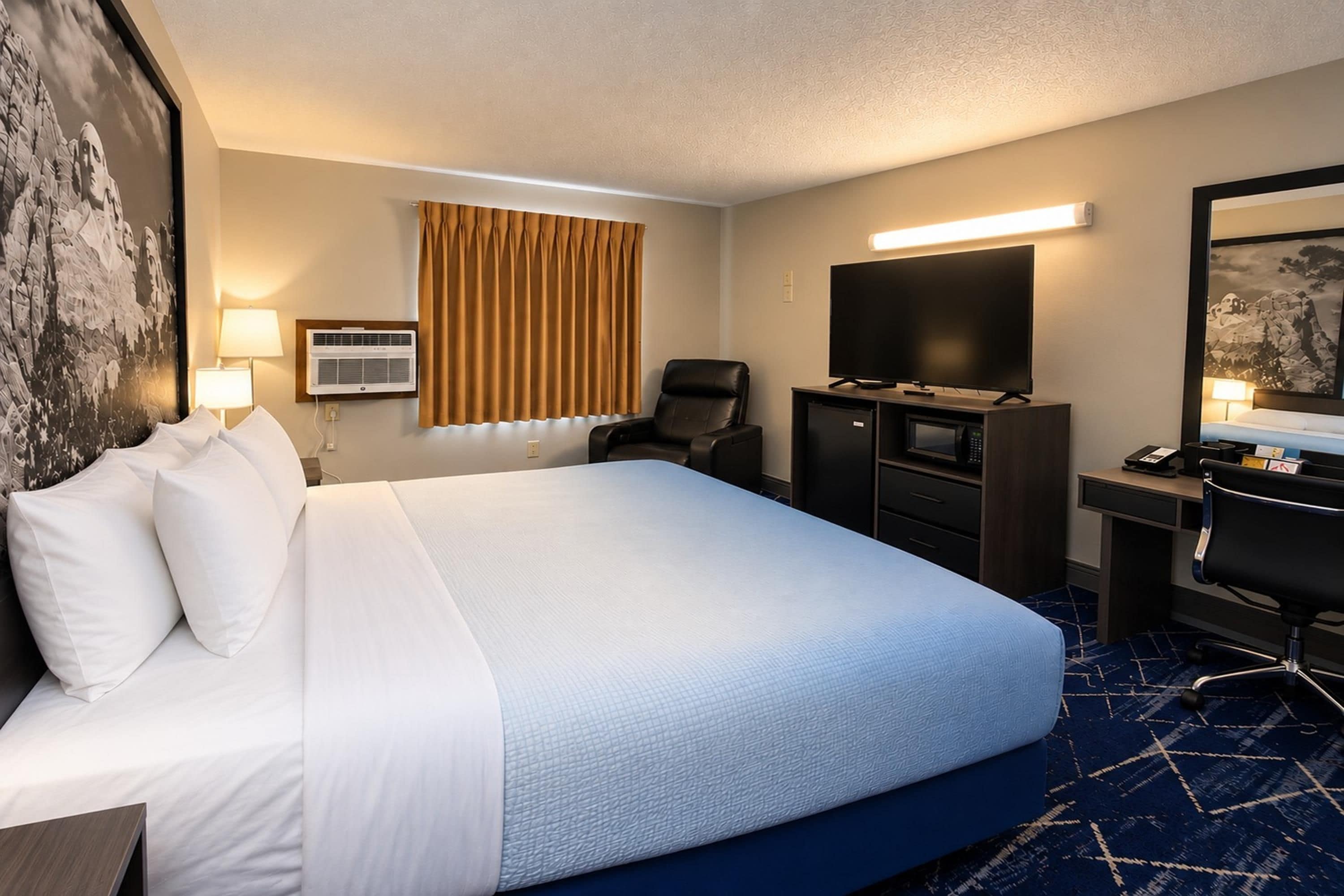 Une chambre d’hôtel avec un grand lit, un bureau avec une chaise, une télévision et un climatiseur fixé au mur.