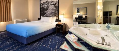A hotel room with a bed, a desk, a large window with curtains, a bathtub, and a bathroom with a mirror and sink.
