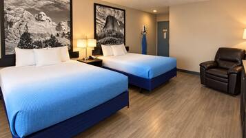 A hotel room with two beds, a chair, and artwork on the walls.