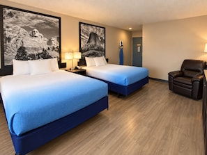Une chambre d’hôtel avec deux lits, une chaise et des œuvres d’art accrochées aux murs.