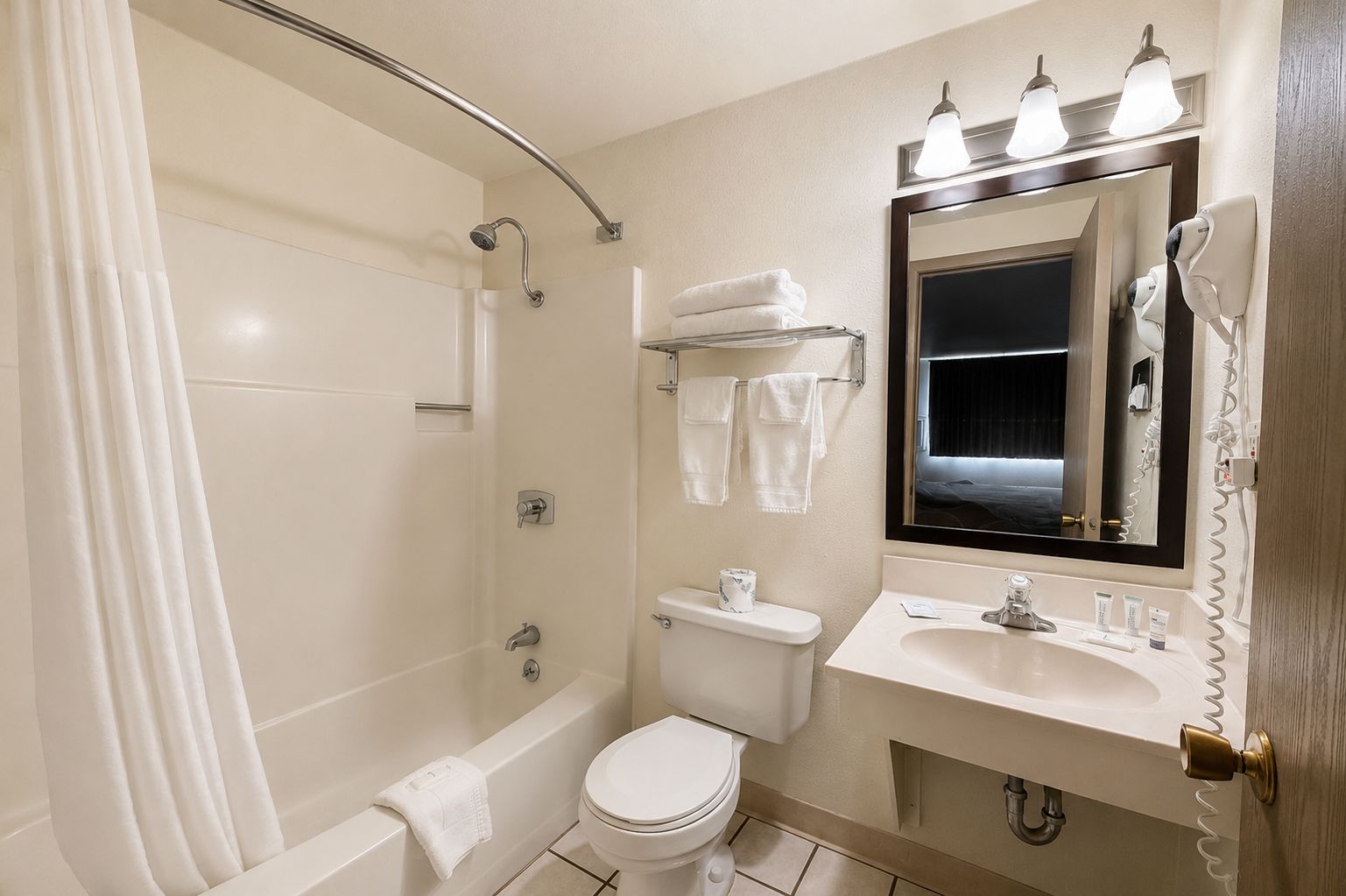 A bathroom with a bathtub, toilet, sink, and a mirror with lights.