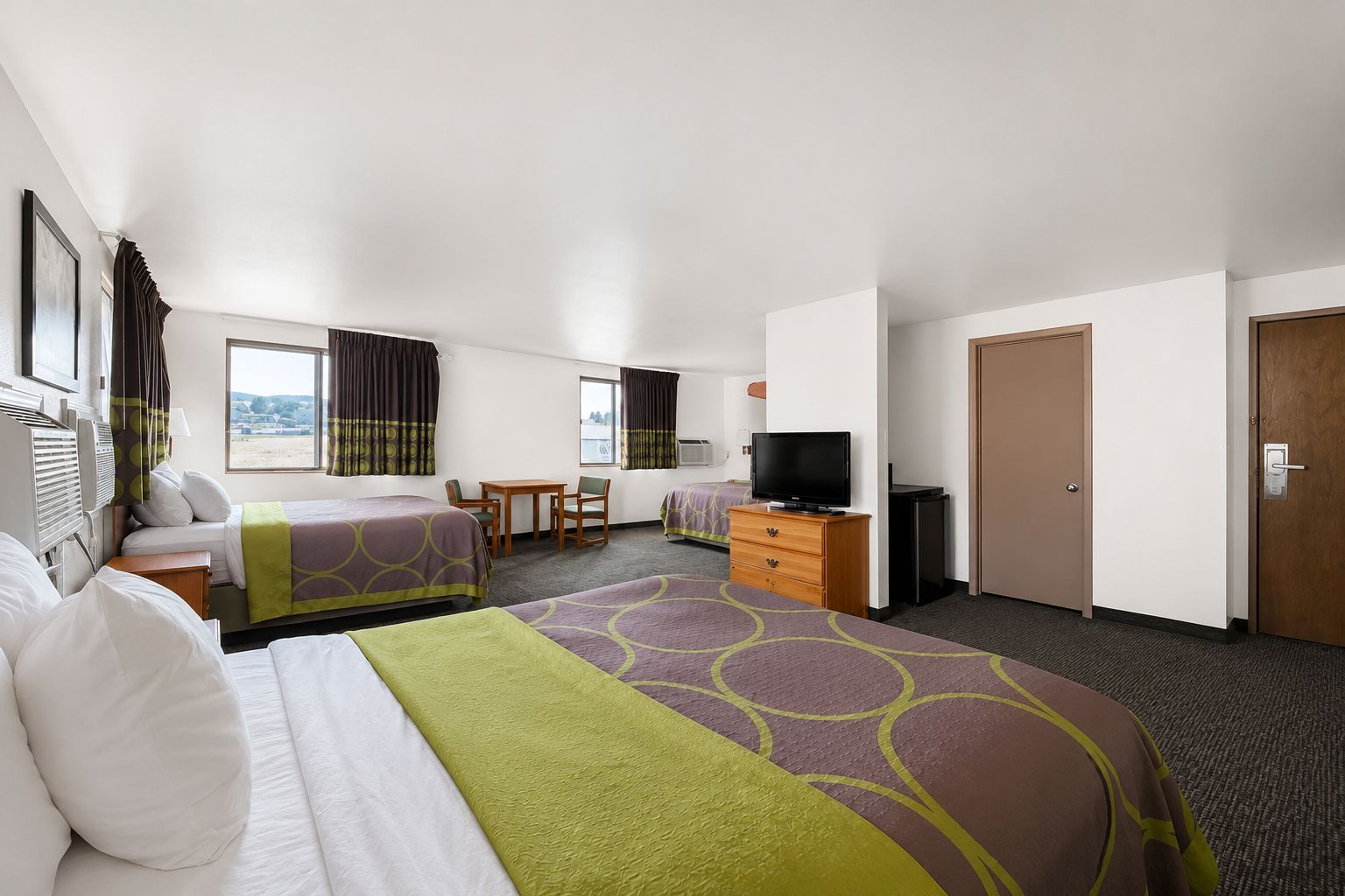 A hotel room with two beds, a desk, a television, and a wardrobe.