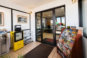 A hotel lobby with a reception desk, a magazine rack, and a door leading to the dining area. - FairBridge Inn & Suites Spearfish (Spearfish)