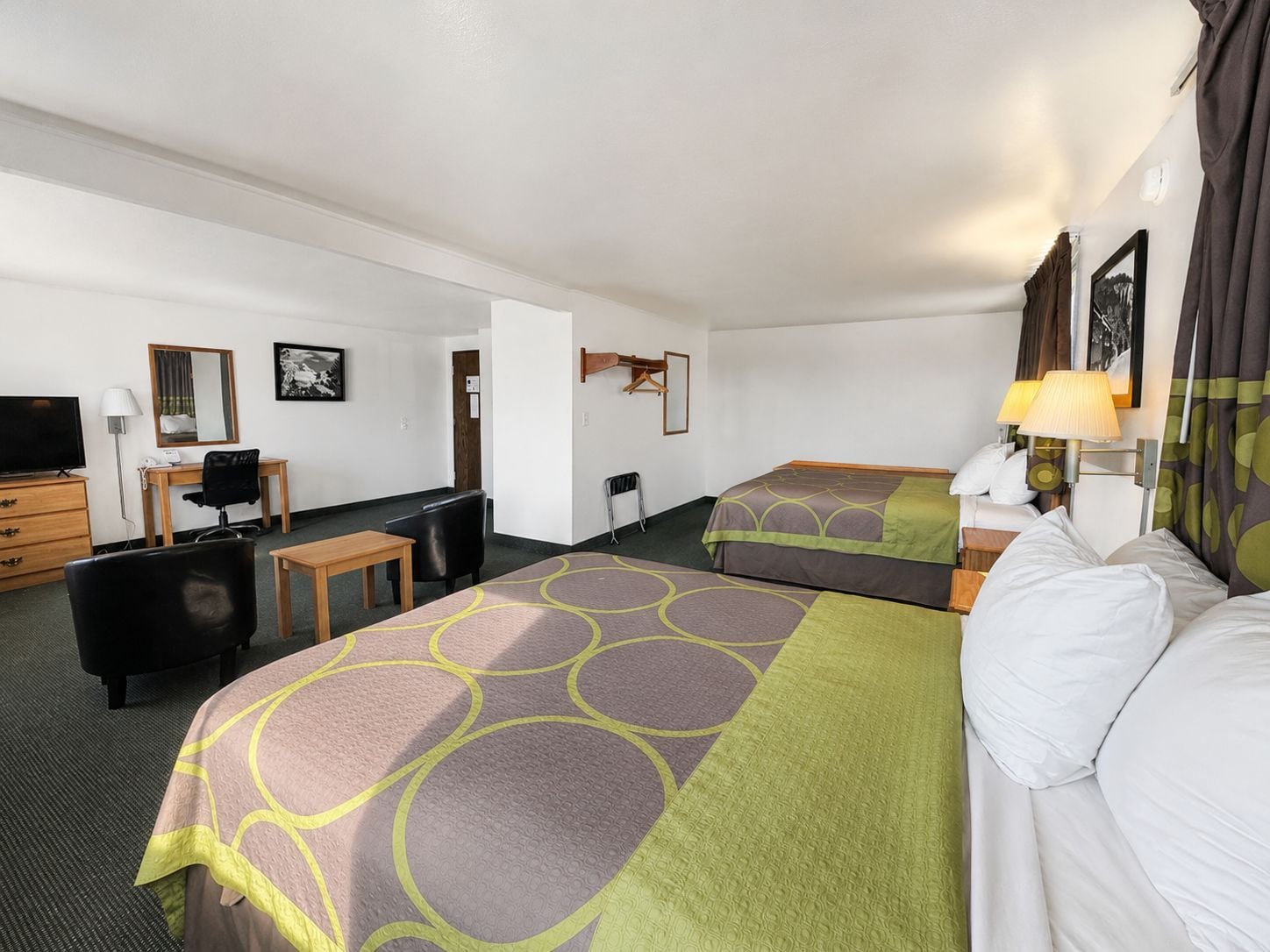 Habitación de hotel con dos camas, un escritorio, una silla, un televisor y un espejo.