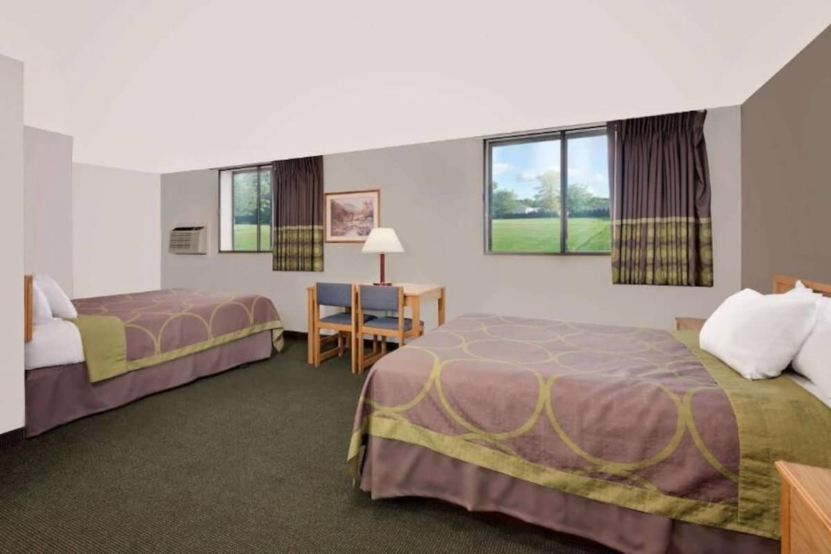 A hotel room with two beds, a desk, and a chair.