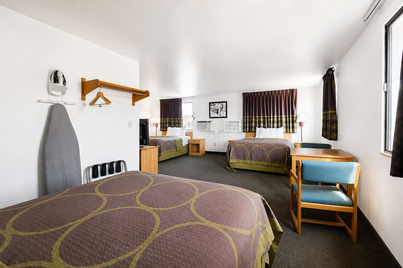 A hotel room with two beds, a desk, and a chair.