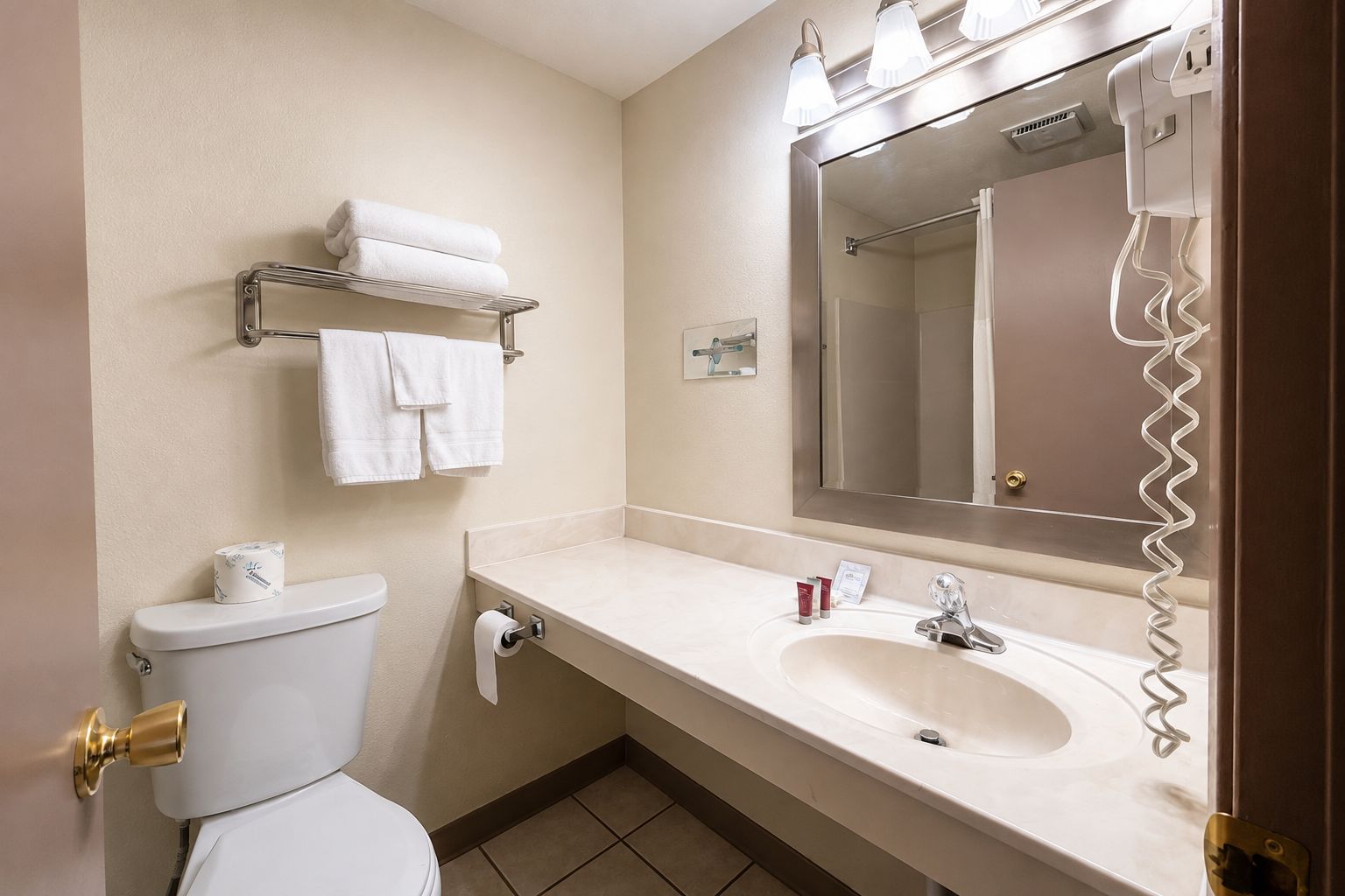 A hotel bathroom with a toilet, sink, and a towel rack.