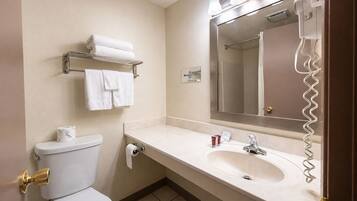 A hotel bathroom with a toilet, sink, and a towel rack.