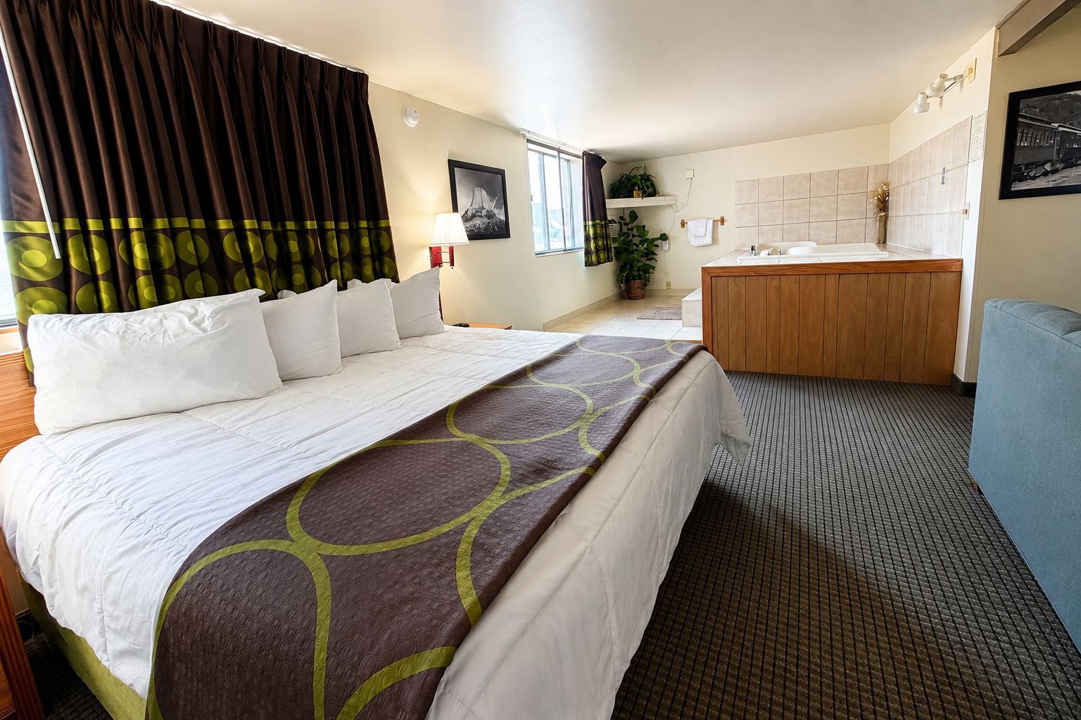 A hotel room with a bed, a desk, a chair, a bathroom, and a window with curtains.