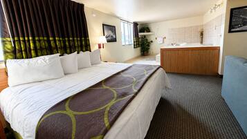 A hotel room with a bed, a desk, a chair, a bathroom, and a window with curtains.