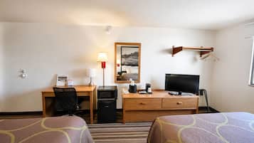Quarto de hotel com escrivaninha, computador, televisão, micro-ondas, cafeteira, telefone e duas camas.