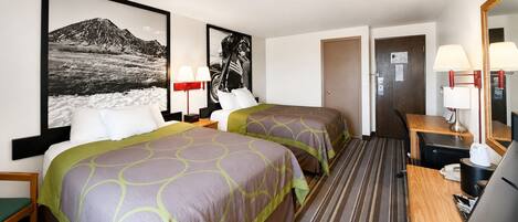 A hotel room with two beds, a desk, a chair, a television, and a bathroom door.