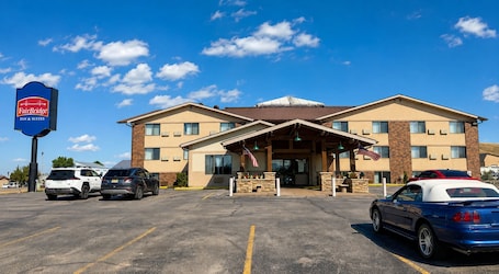 A FairBridge Inn & Suites with a parking lot, a covered entrance, and an American flag.