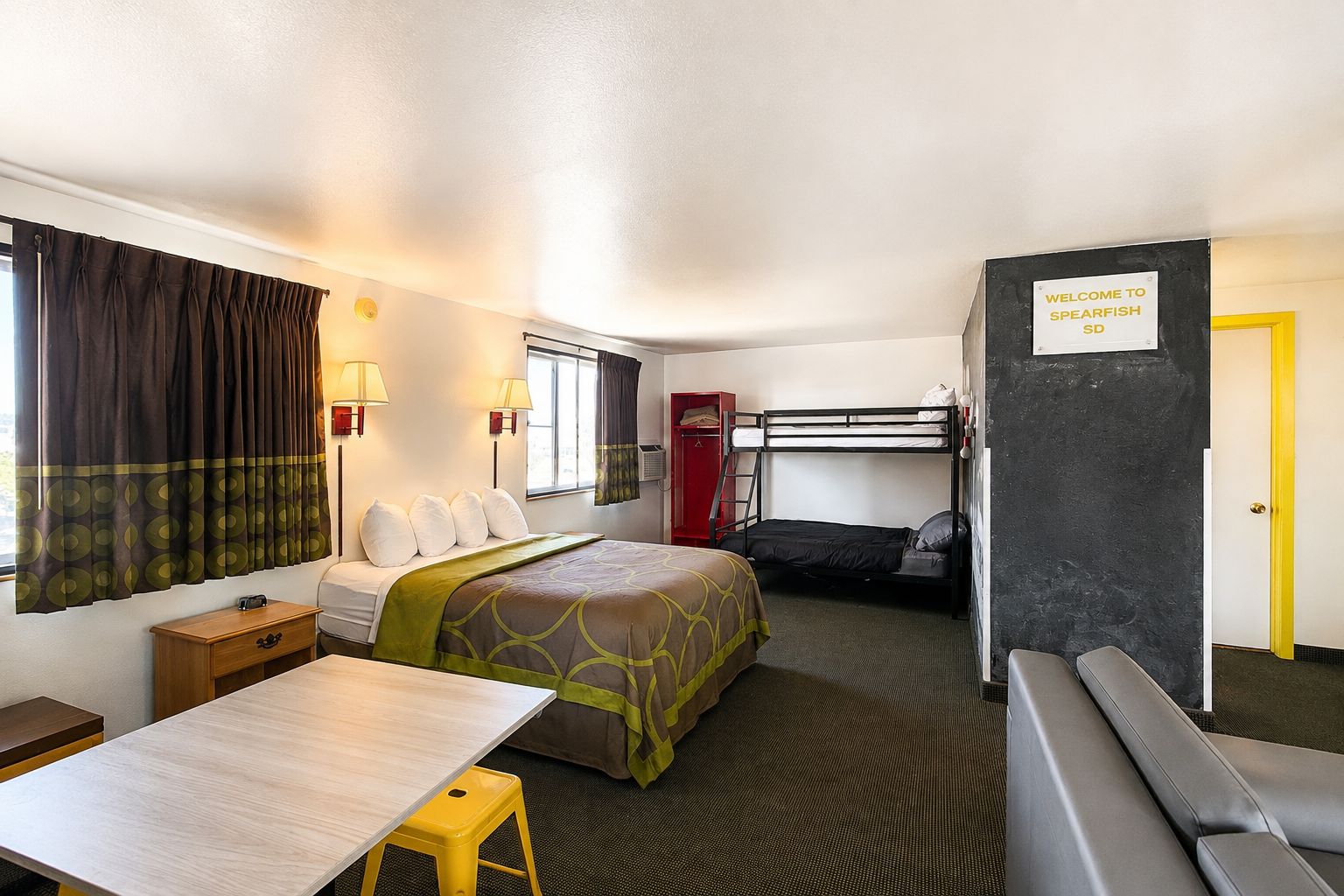 Habitación de hotel pequeña con literas, una cama individual, un escritorio y una zona de estar.