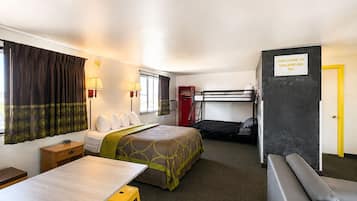 Habitación de hotel pequeña con literas, una cama individual, un escritorio y una zona de estar.