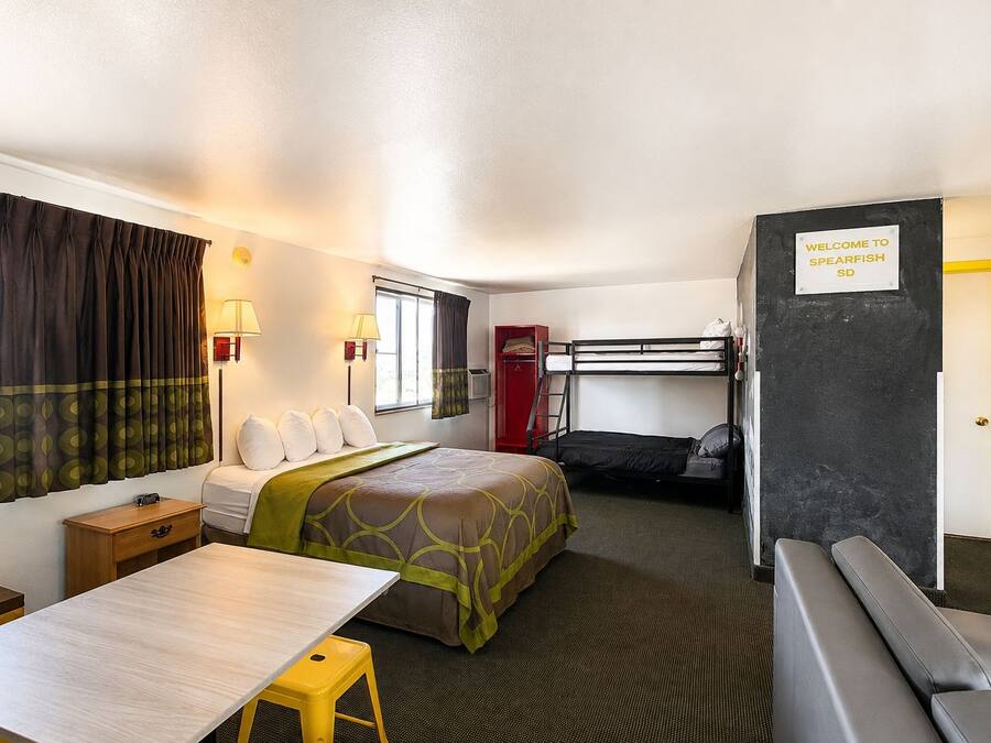 Habitación de hotel pequeña con literas, una cama individual, un escritorio y una zona de estar.